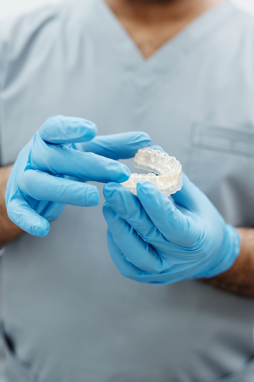 Dentist holding clear dental Invisalign with gloved hands