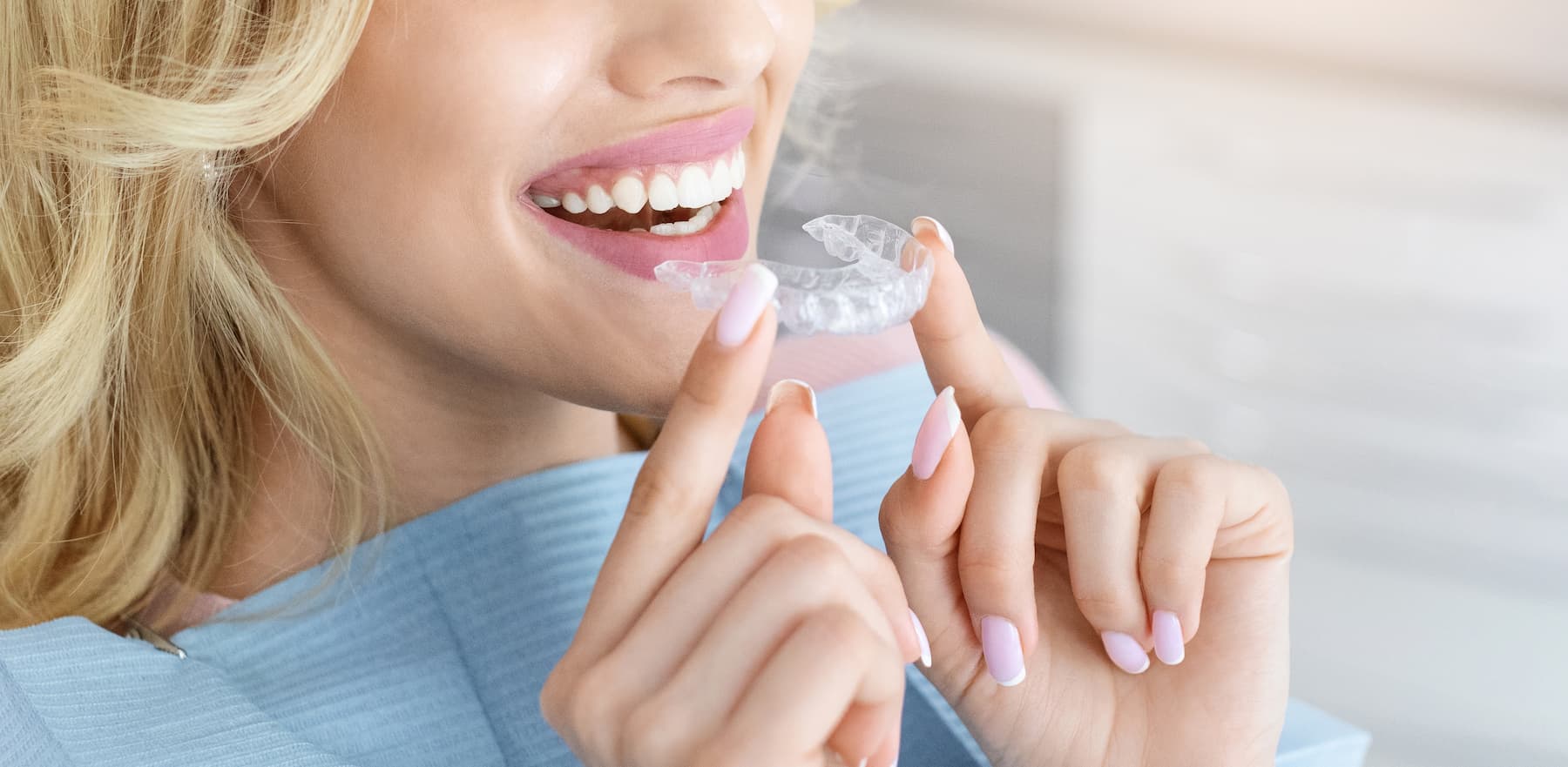 Woman holding clear Invisalign dental retainer